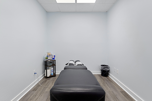 Examination room at the Dalton clinic with a black examination table and a side table of wellness supplies.