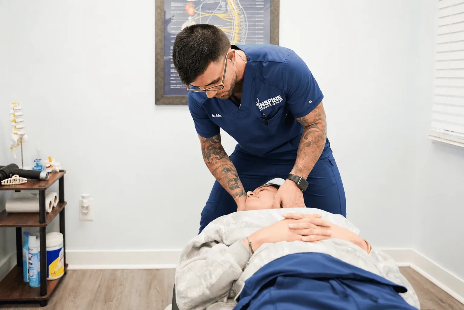 A chiropractor performing a gentle cervical adjustment on a patient lying on a treatment table.