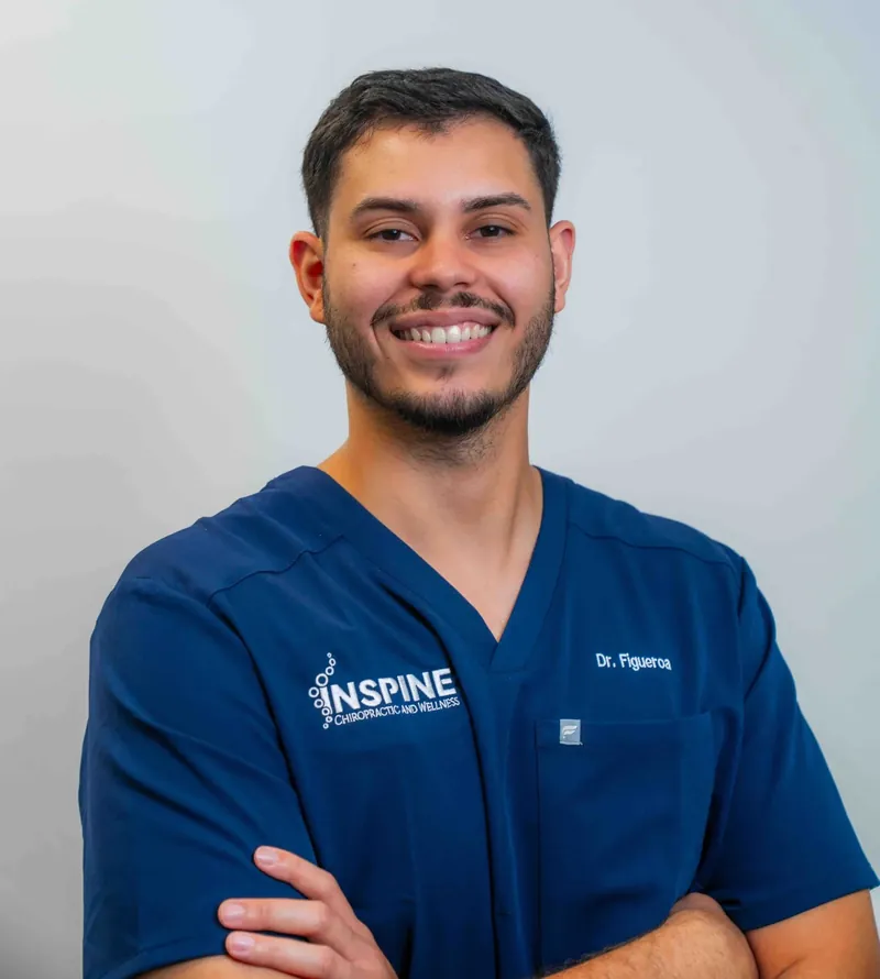 Dr. Jan Figueroa in navy Inspine scrubs, arms folded, in a studio portrait.