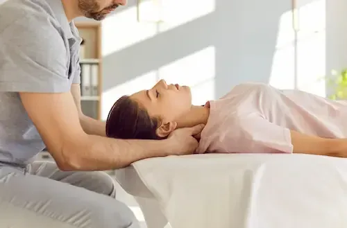 A clinician supporting a patient's head during a gentle neck adjustment.