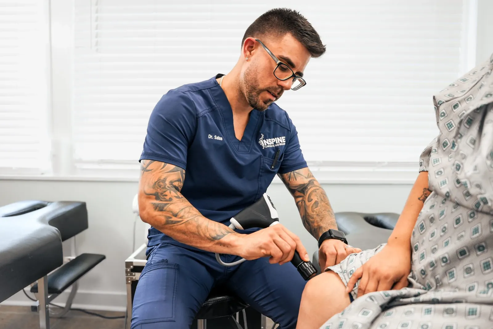 A clinician applying a shockwave therapy handpiece to a patient's knee.