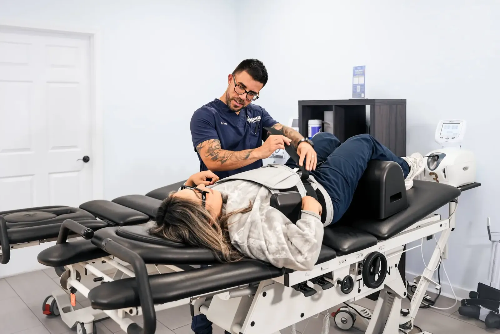 A chiropractor fitting a patient into the harness of a spinal decompression table.
