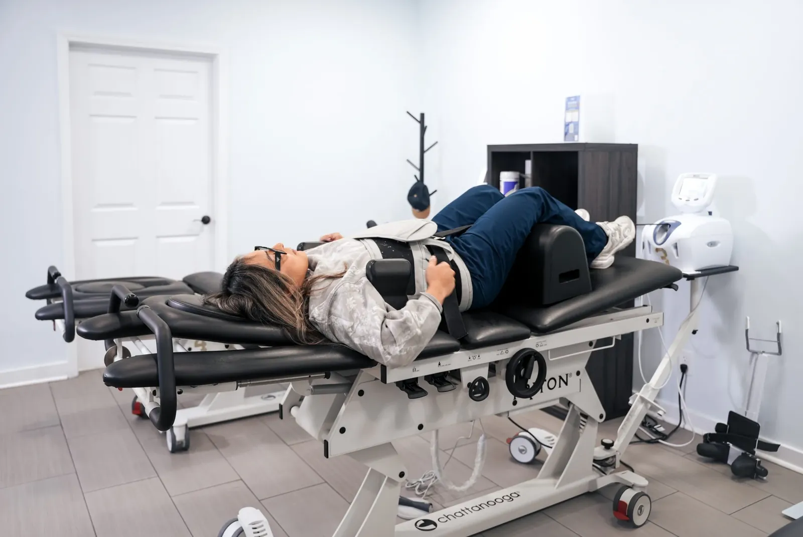 A patient lying on a motorized spinal decompression table with the traction harness fitted.
